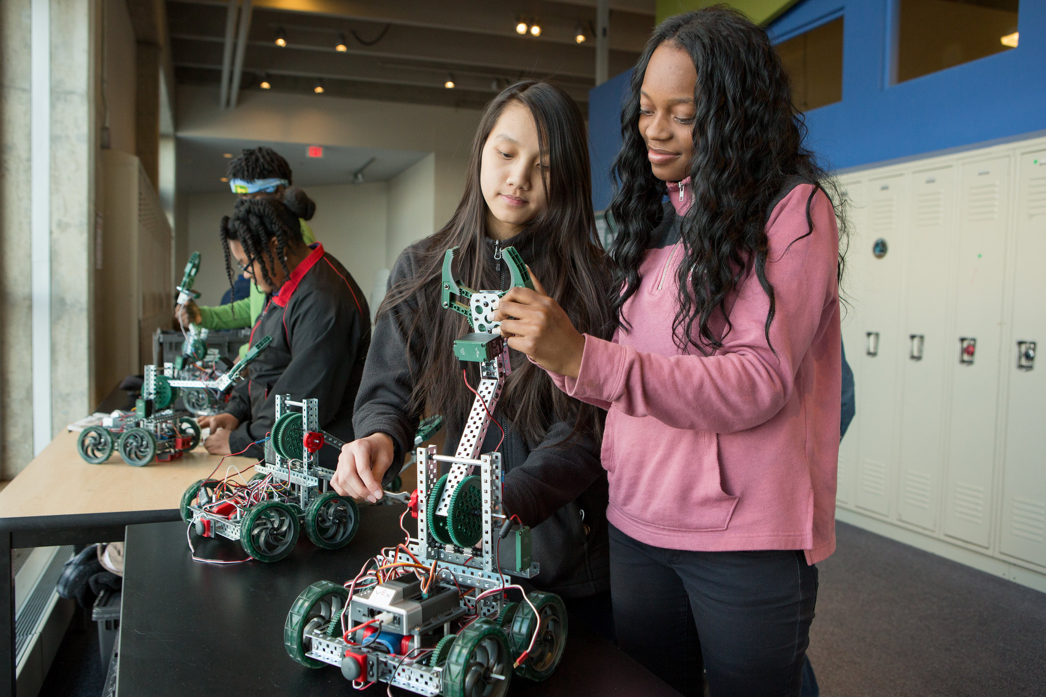 Two teenagers assemble a robot at their school.