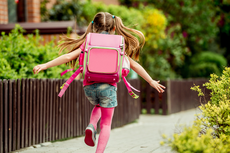 A little girl skips happily outside.