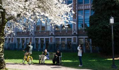 People sit, watch and ride bikes along a college campus.