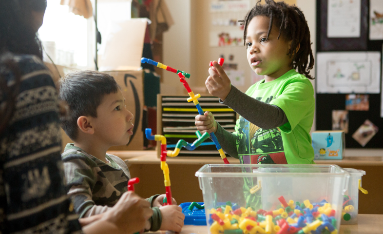 Two small children play with toys that connect to each other.