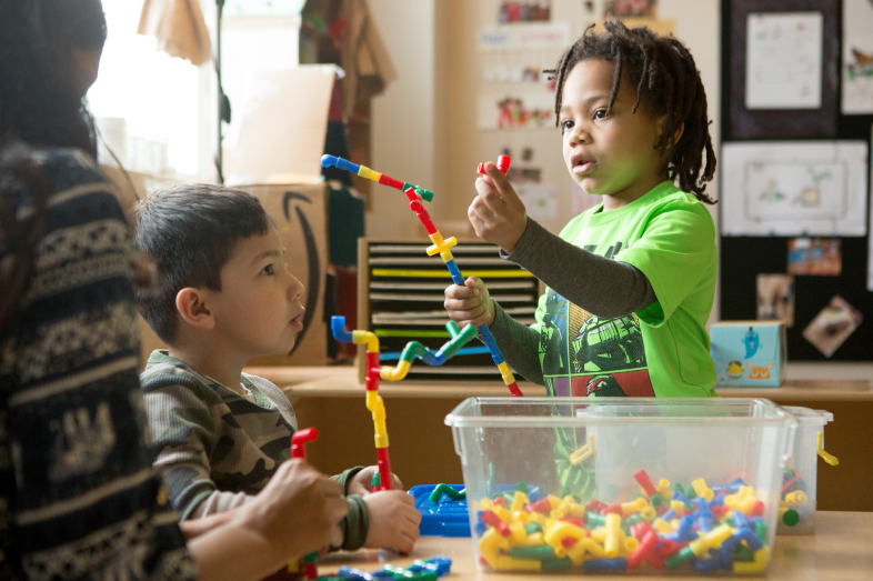 Two small children play with toys that connect to each other.