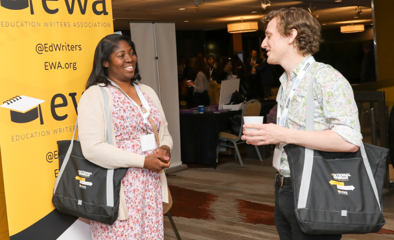 A Black woman and a white man face each other as they speak to each other at a conference.