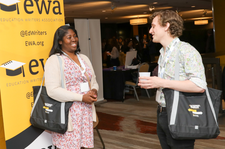 A Black woman and a white man face each other as they speak to each other at a conference.