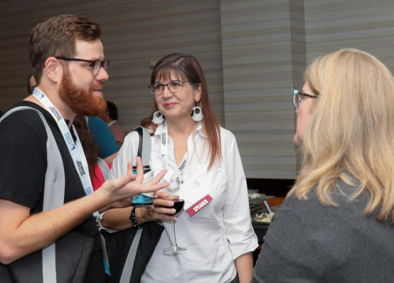 Three people talk at a networking event.