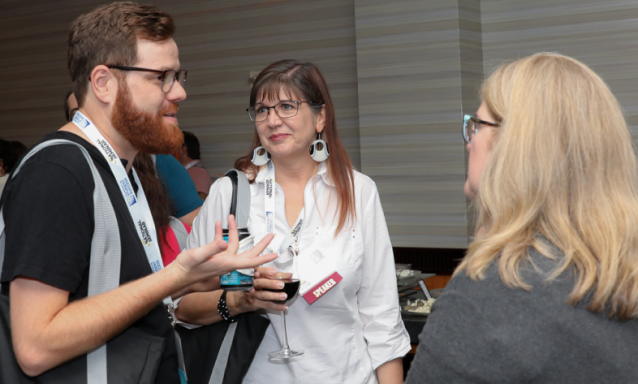 Three people talk at a networking event.