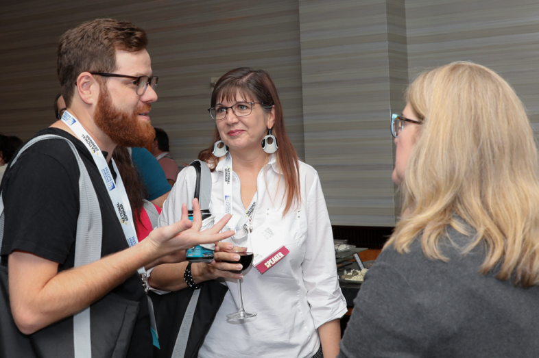 Three people talk at a networking event.