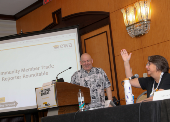 Two people laugh and chat during a panel discussion.