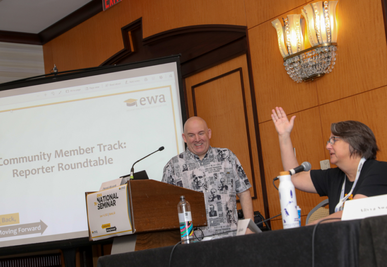 Two people laugh and chat during a panel discussion.