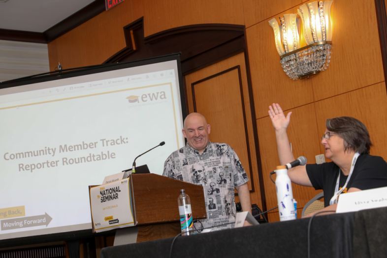 Two people laugh and chat during a panel discussion.