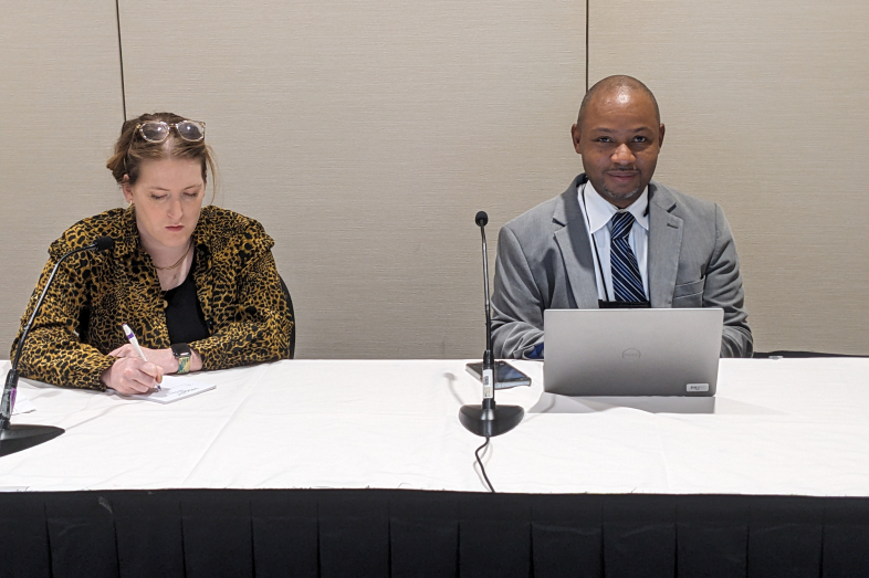 A man and a woman sit at a table next to each other.